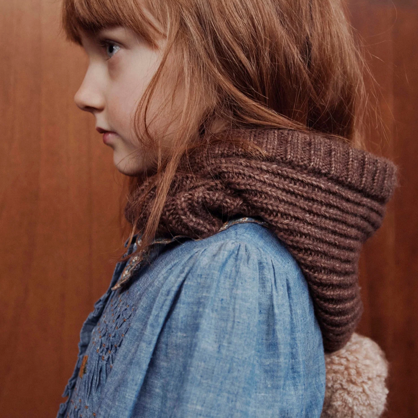 Person wearing a brown knitted scarf with a blurred background