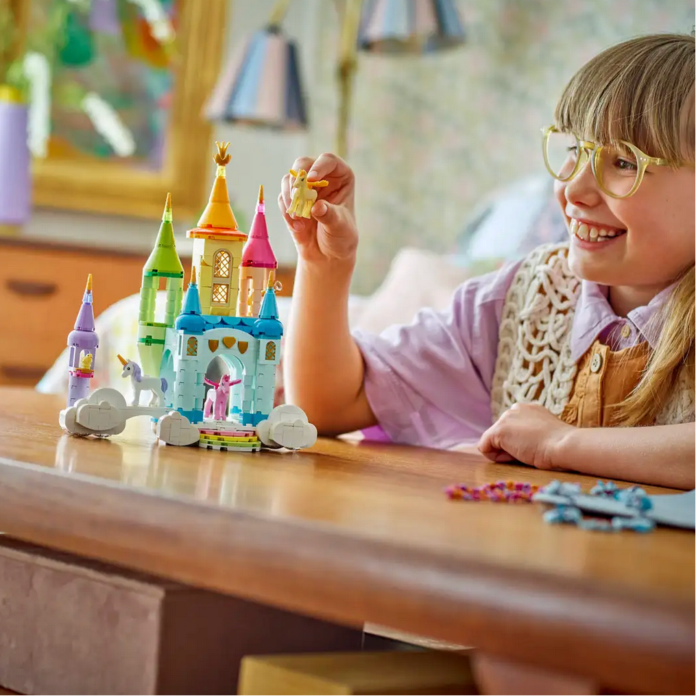 Child playing with a toy castle set on a wooden table