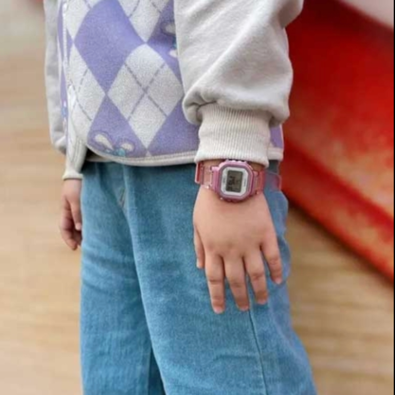 Child wearing a pink digital watch with a blurred background