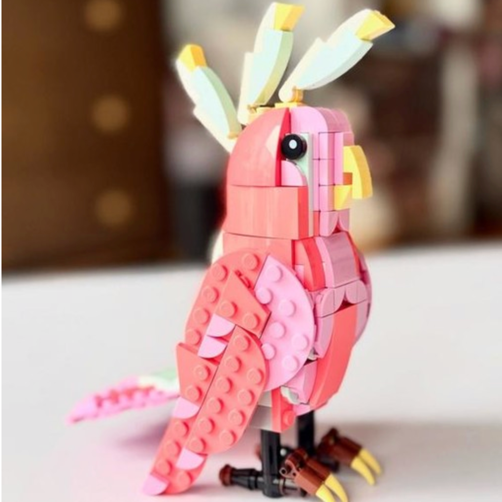 Pink parrot made of interlocking bricks on a white surface with a blurred background