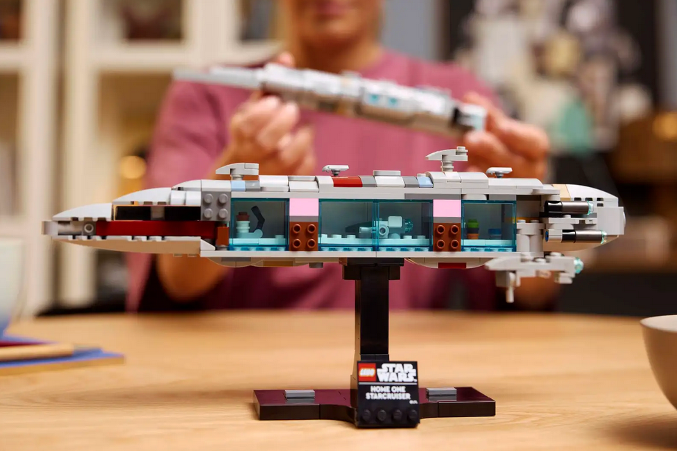 LEGO model of a spaceship on a stand with a person in the background