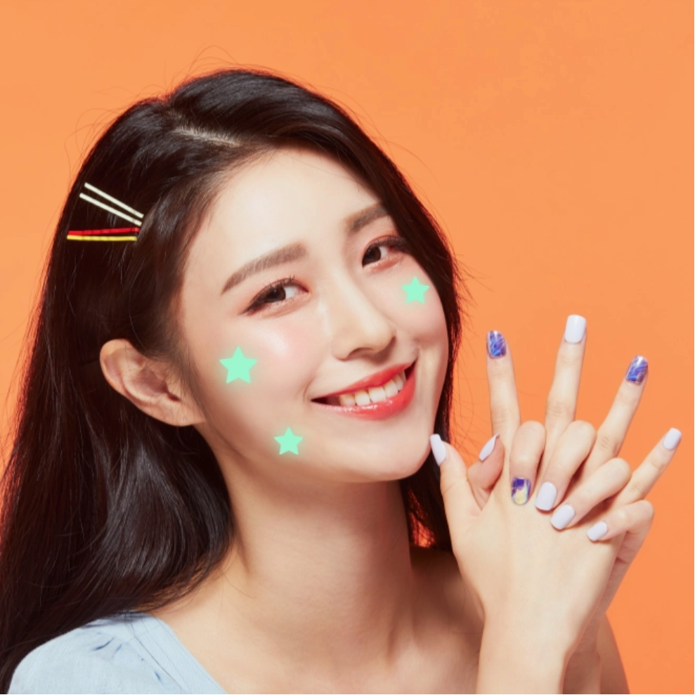 Woman with decorative stars on her face and hands against an orange background
