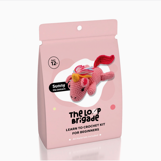 Crochet kit packaging with a pink unicorn toy on a white background