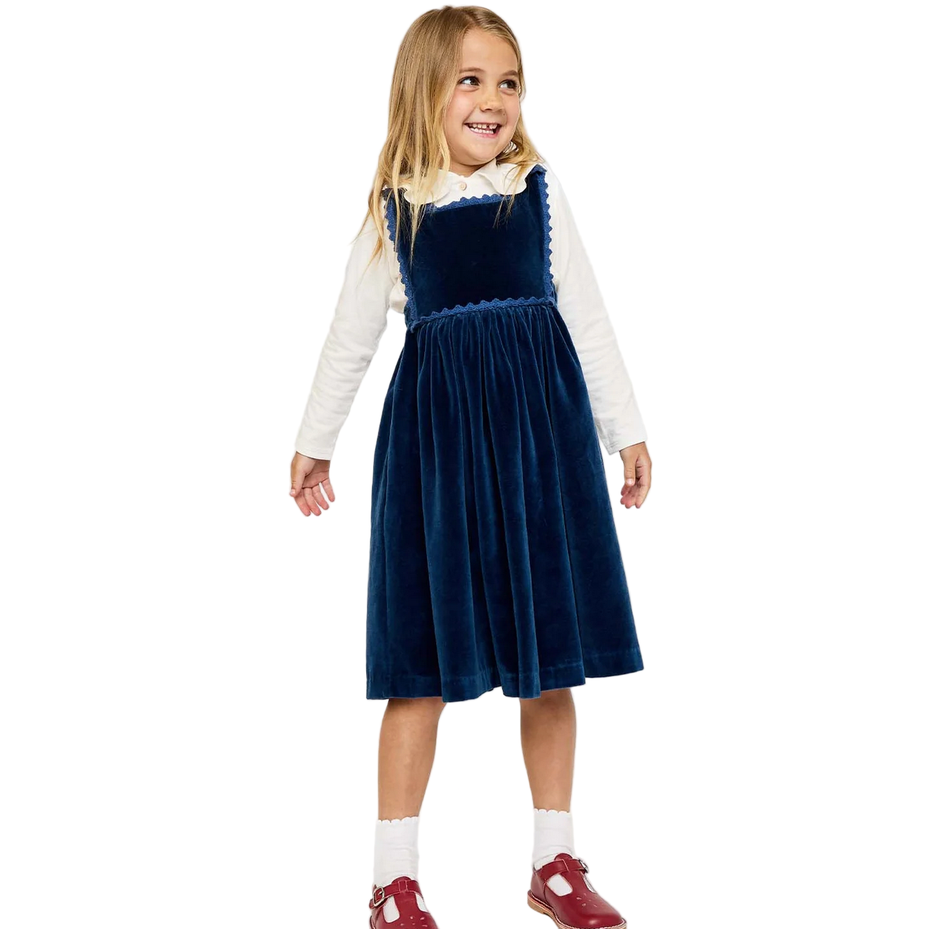 Young girl wearing a blue velvet dress with a white shirt underneath on a white background.
